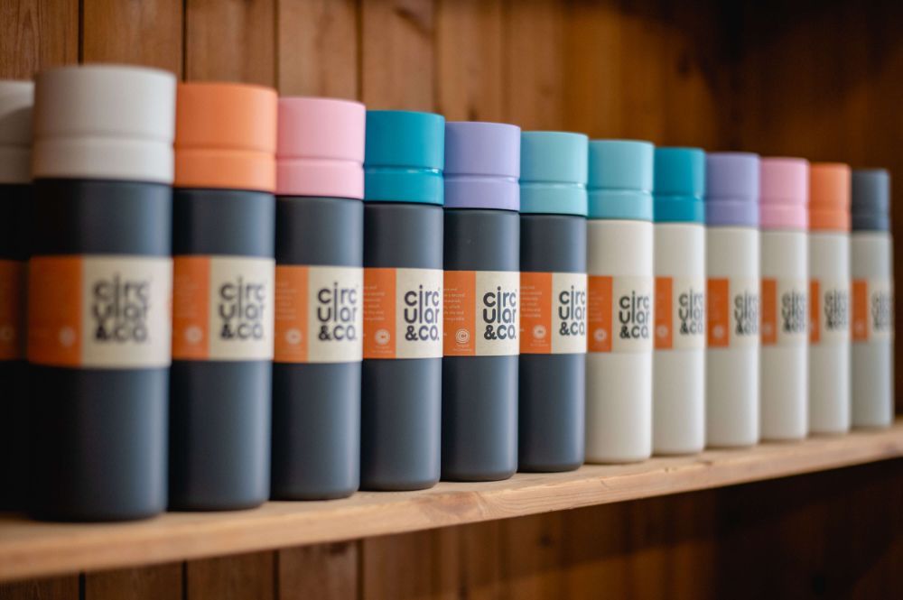 Circular&Co. reusable water bottle range arranged on wooden shelf.