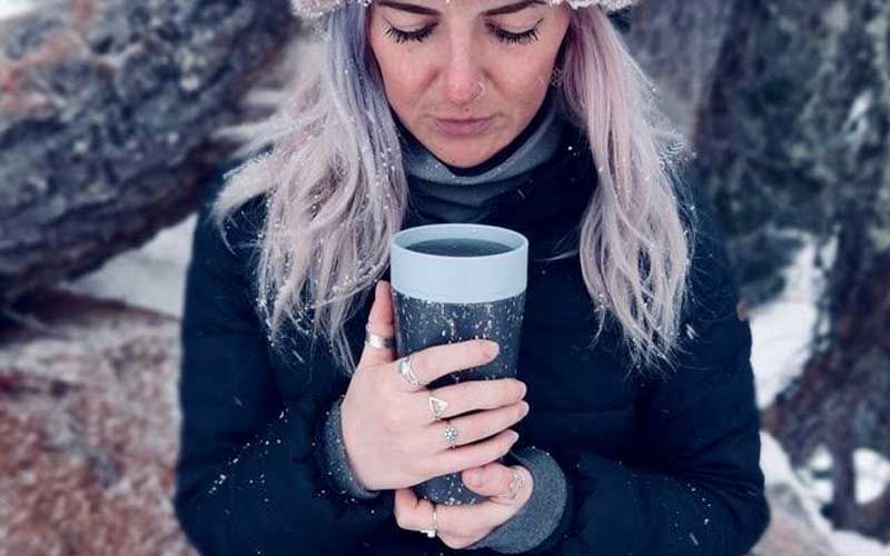 A woman uses a hot drink in her Circular&Co. Cup to keep warm in the snow