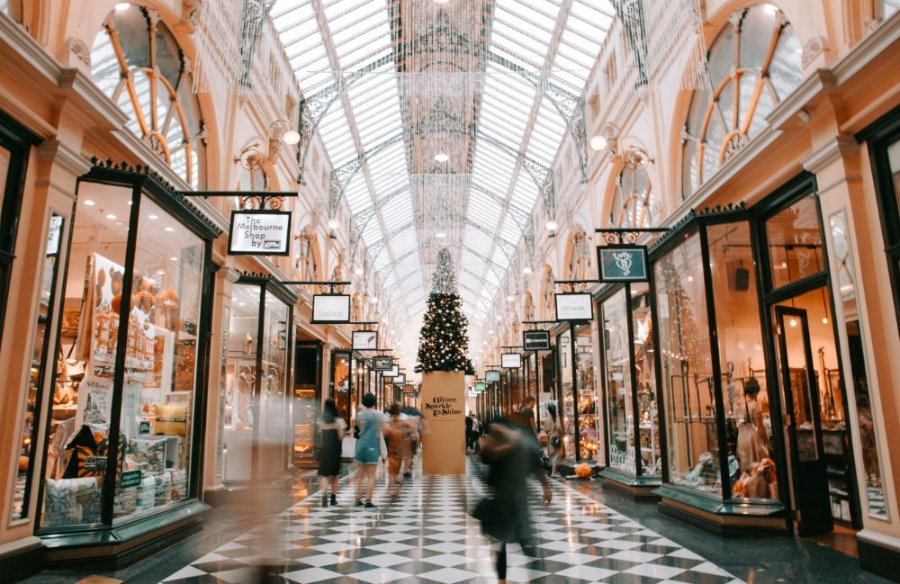 People walking through shopping centre aisle under Christmas decorations.