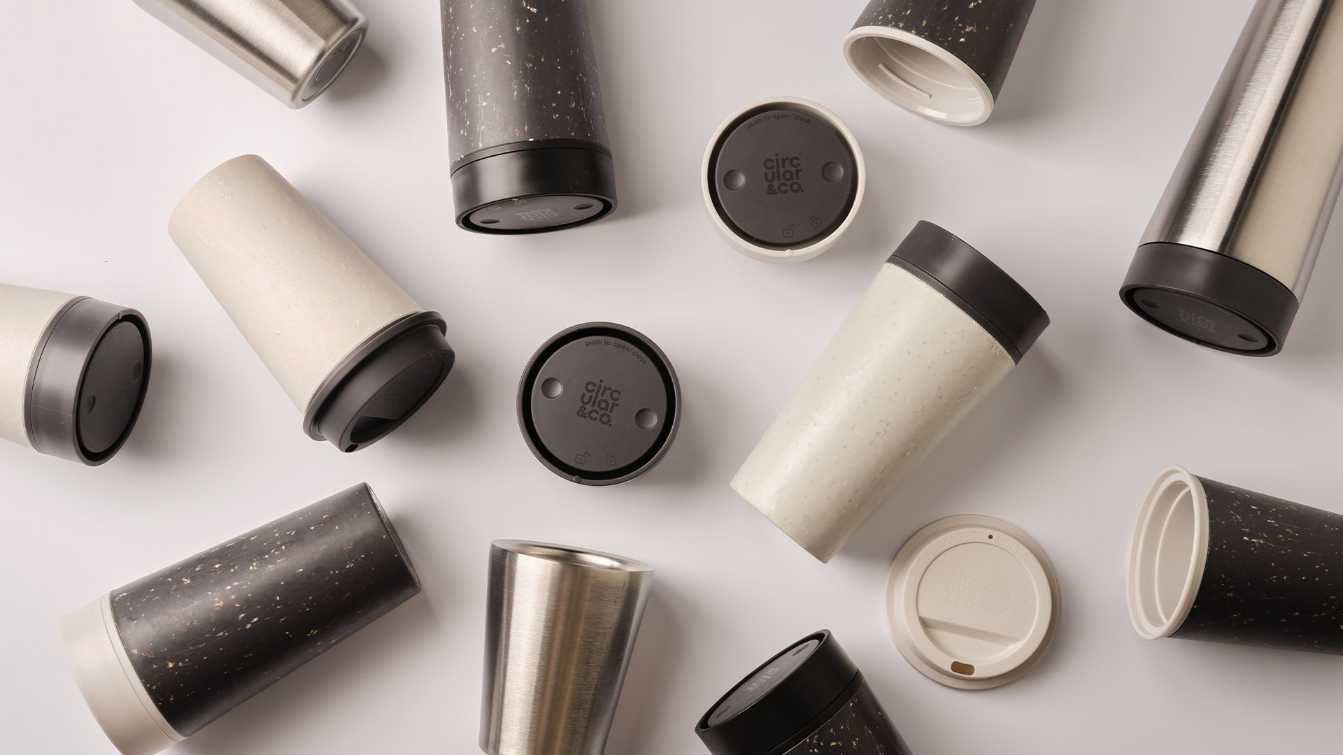 black, white and steel reusable cups on a white table