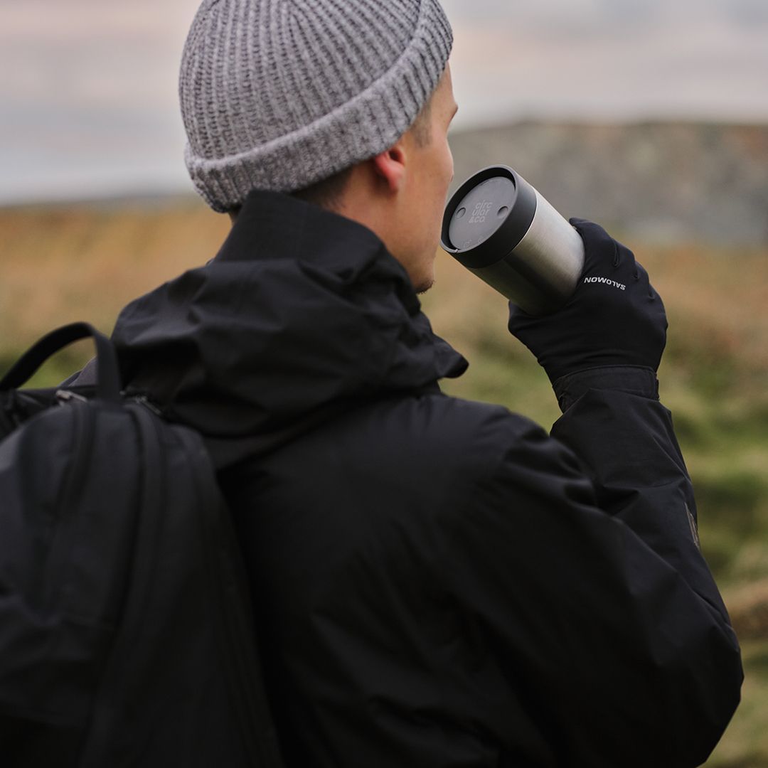 man drinking from steel reusable cup