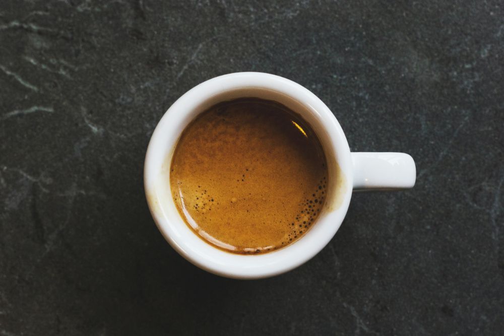 White ceramic coffee mug on black slate counter top viewed from above.