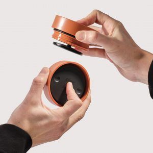 hands holding orange reusable cup lids