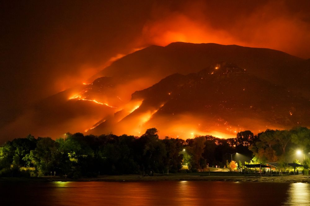 Forest fire engulfing huge hill of trees behind a small town.