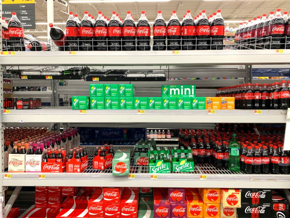 Supermarket shelves stocked with different sized soft drinks.