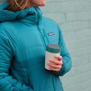 woman holding white reusable cup with blue lid