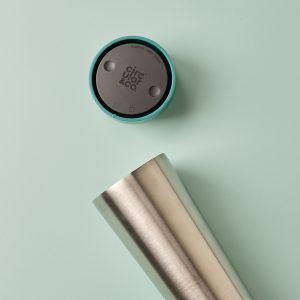 steel reusable cup with green lid on green surface