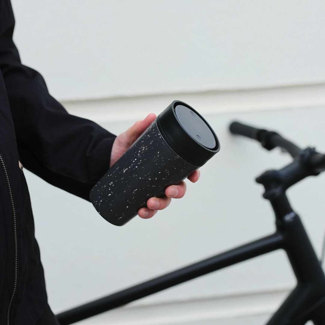 man holding black reusable cup with black lid