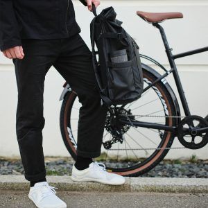 man holding backpack with black reusable cup in the side pocket