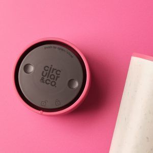 pink cup lid on pink table, next to white reusable cup