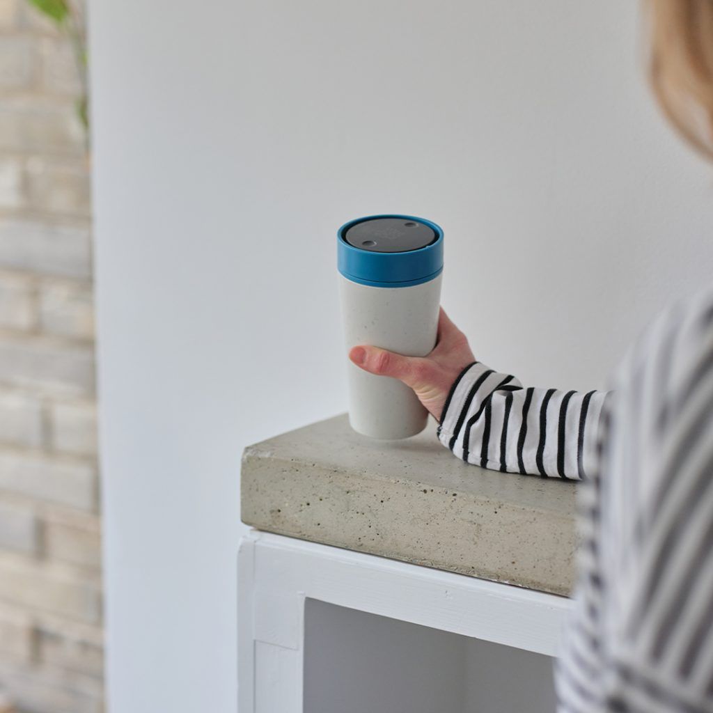 woman in striped top holding her reusable cup