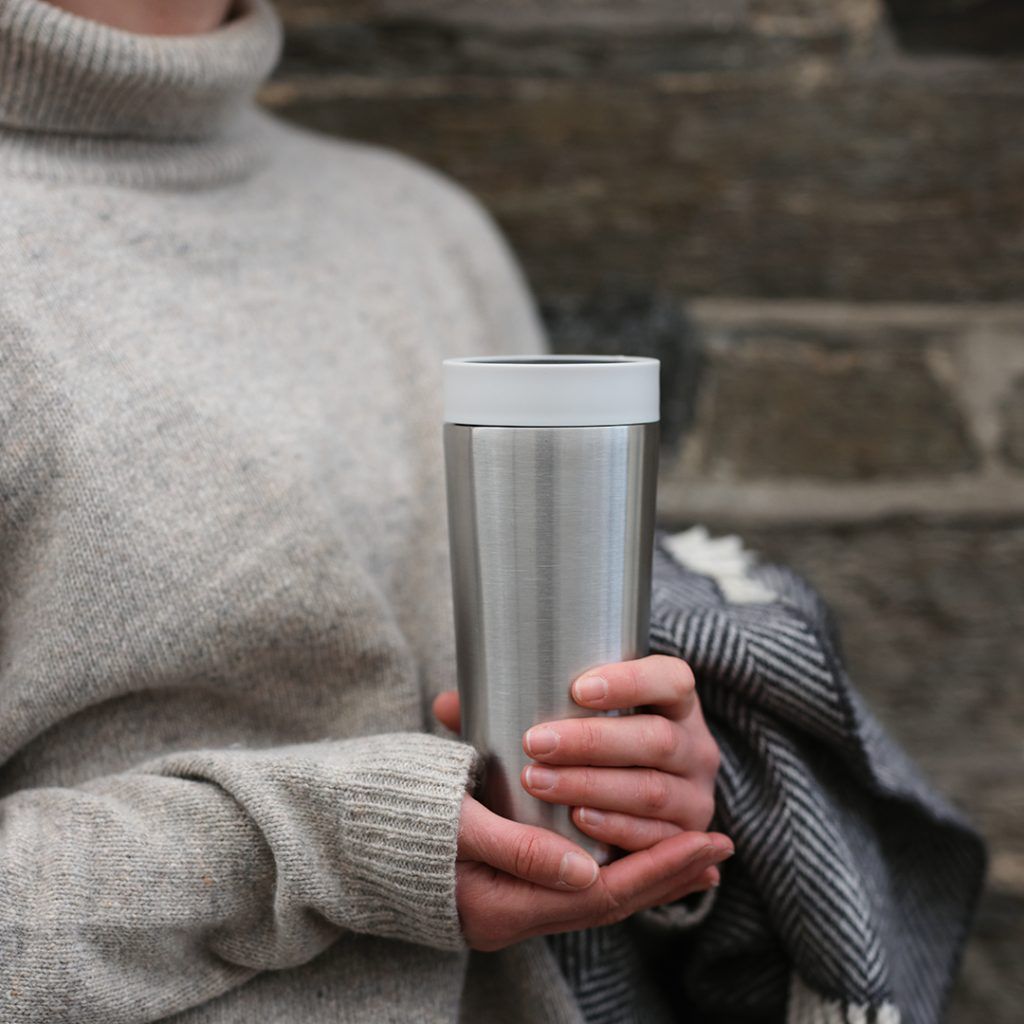 woman holding steel reusable cup with white lid