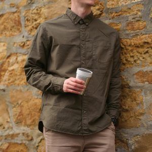 man in green shirt holding steel reusable cup with white lid