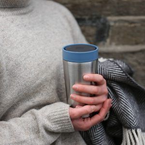 woman holding steel reusable cup with blue lid