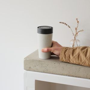 person holding reusable cup at the end of a table