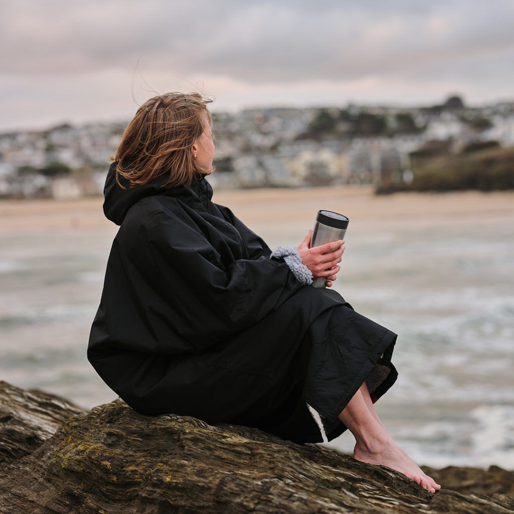 woman sat on rock holding steel reusable cup
