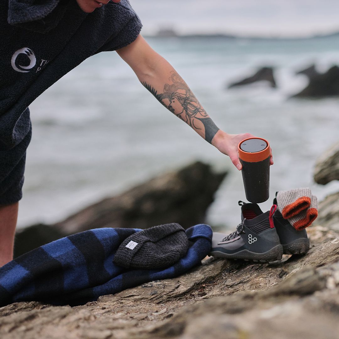 man placing reusable cup into his shoe at the beach
