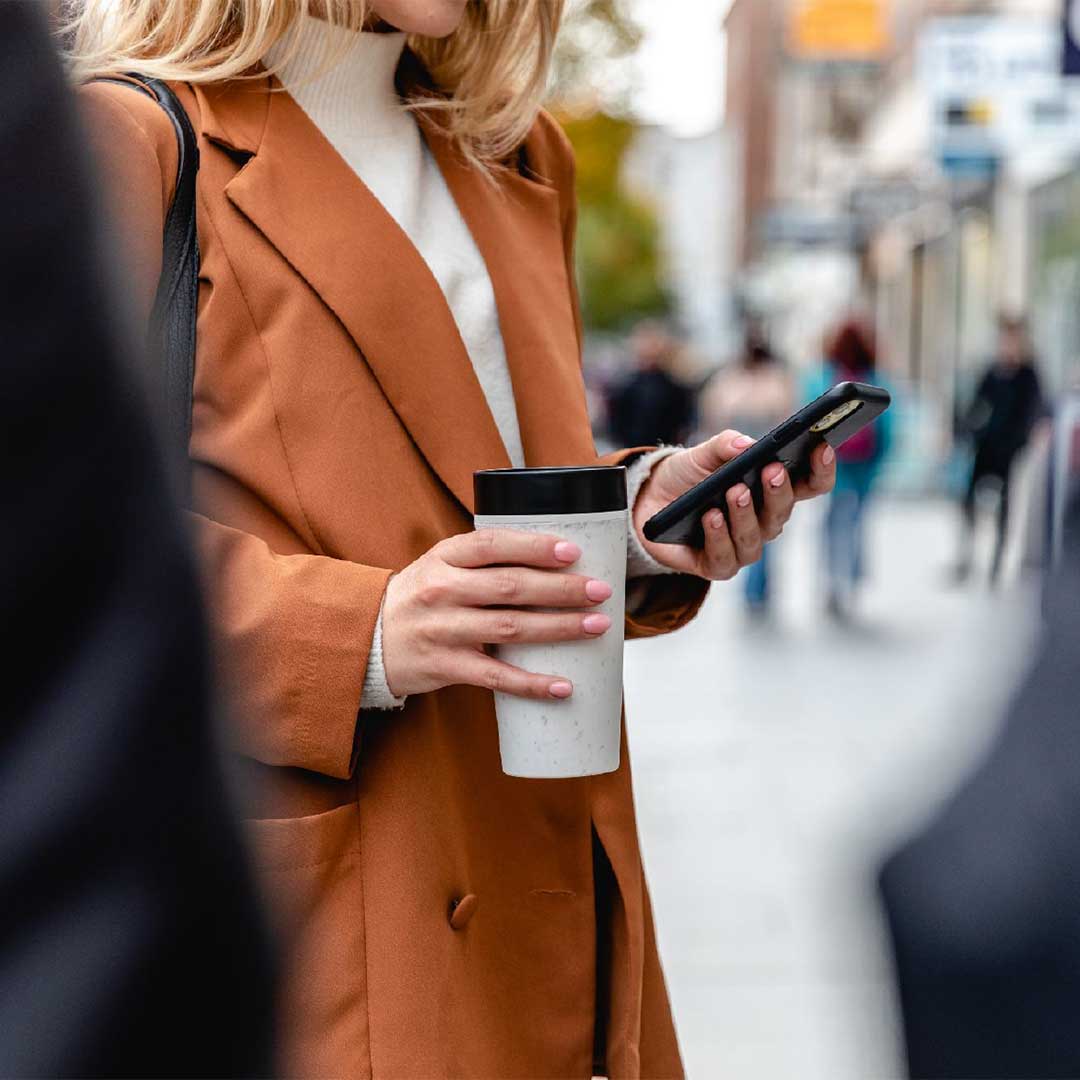 woman holding white reusable cup with blue lid - circular design sustainability