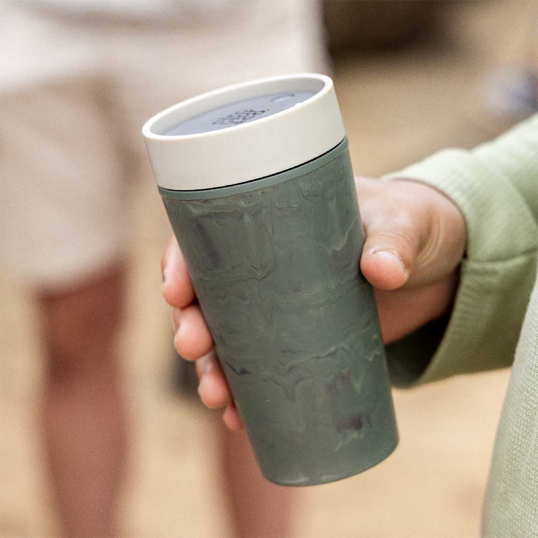woman holding steel reusable cup with blue lid